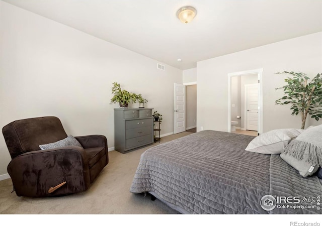 bedroom featuring ensuite bathroom and light colored carpet