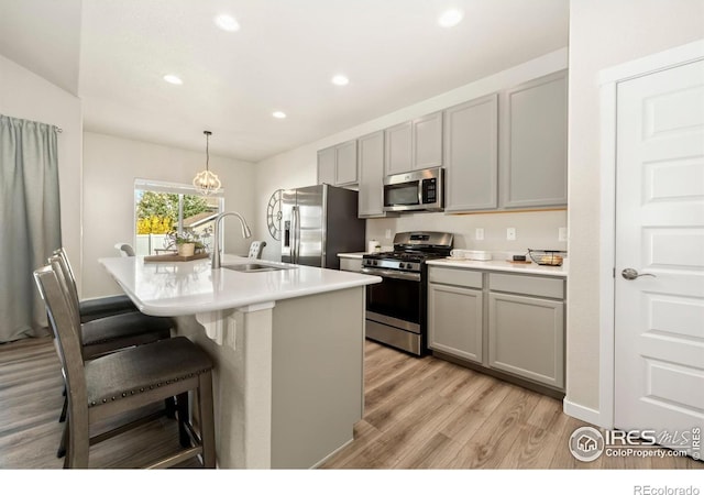 kitchen featuring gray cabinetry, a center island with sink, sink, light wood-type flooring, and appliances with stainless steel finishes