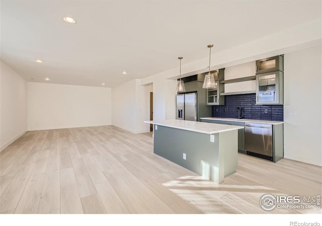 kitchen with a kitchen island, stainless steel appliances, tasteful backsplash, light hardwood / wood-style floors, and hanging light fixtures