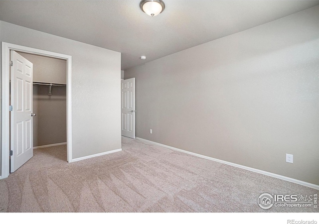 unfurnished bedroom featuring light colored carpet, a closet, and a spacious closet