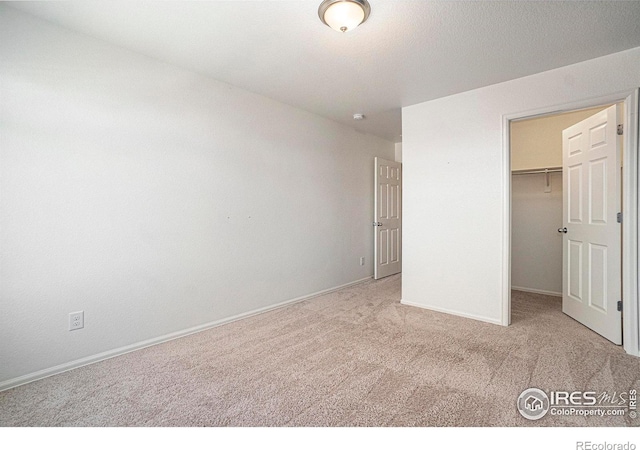 unfurnished bedroom featuring light carpet, a closet, and a spacious closet