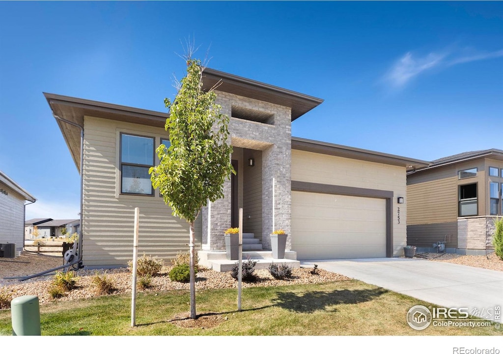 view of front of home featuring a garage, a front lawn, and central air condition unit