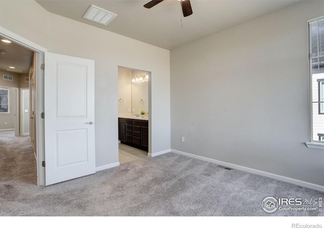 unfurnished bedroom featuring light carpet, ensuite bath, and ceiling fan