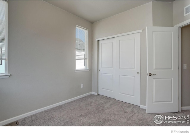 unfurnished bedroom with light colored carpet and a closet