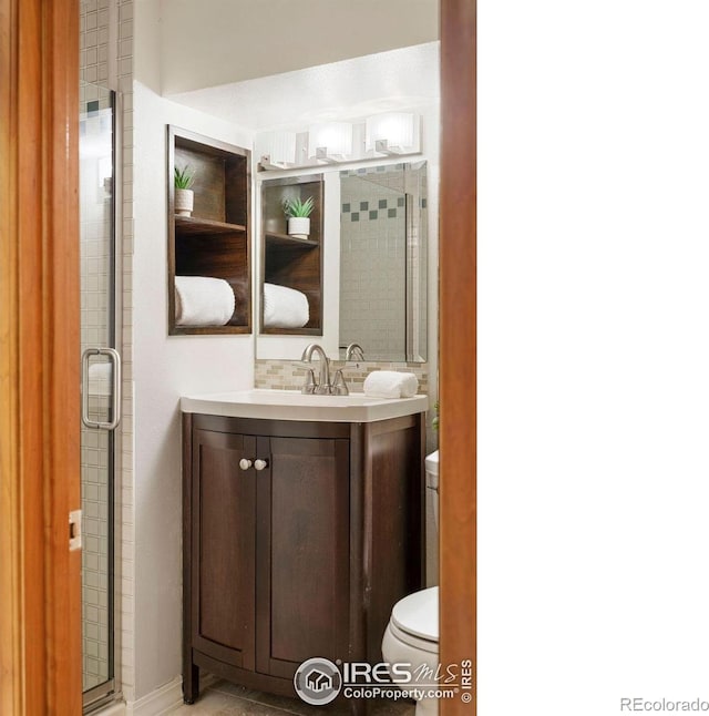 bathroom featuring vanity, toilet, and an enclosed shower