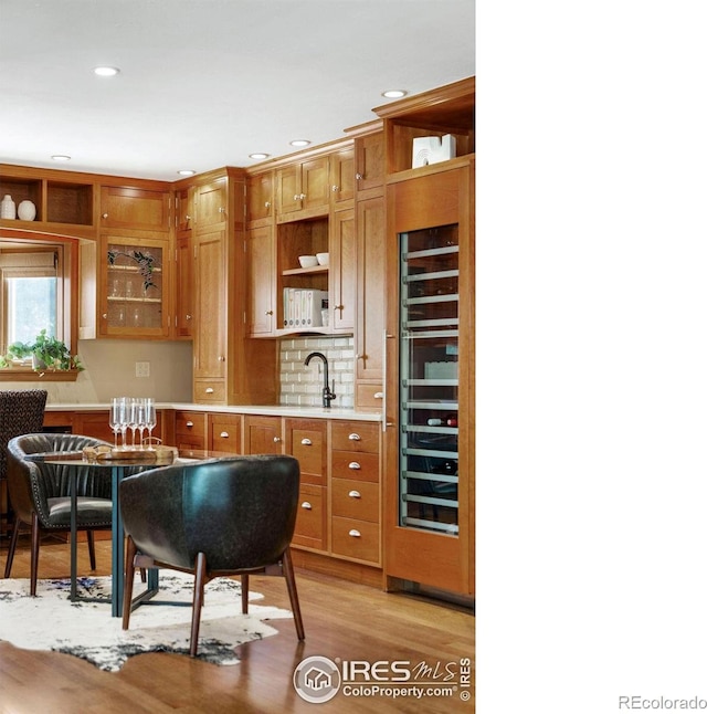 kitchen with wine cooler, sink, and light wood-type flooring