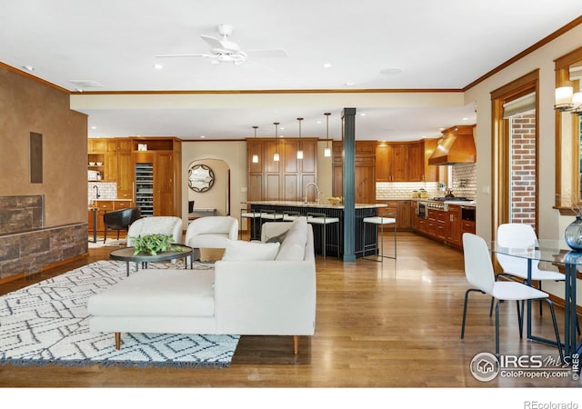 living room featuring crown molding, hardwood / wood-style floors, sink, and ceiling fan