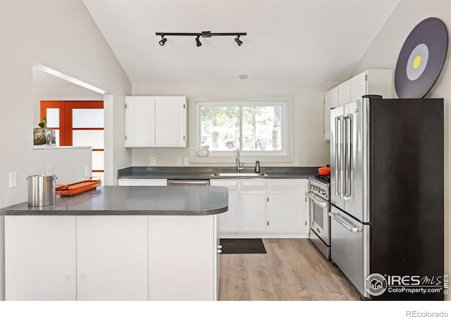 kitchen with sink, vaulted ceiling, white cabinetry, and premium appliances