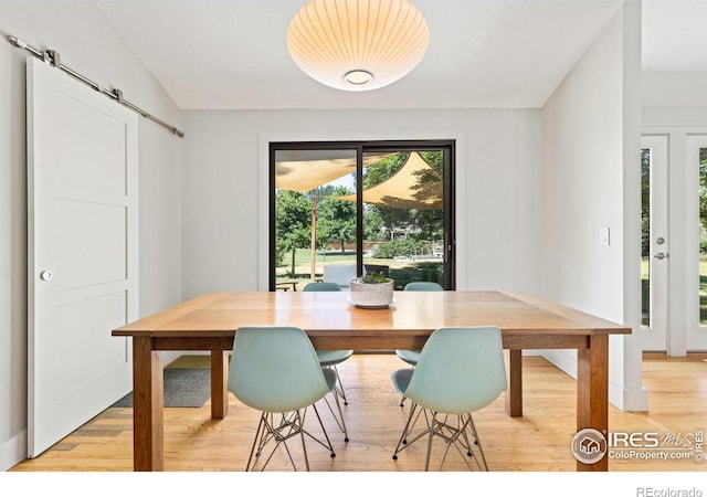 dining space with light wood-type flooring and a barn door