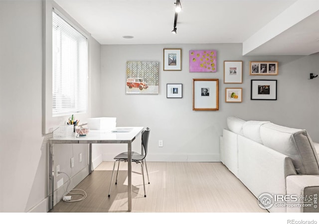 home office featuring rail lighting and light hardwood / wood-style flooring