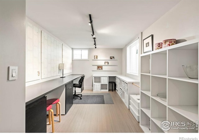 home office with track lighting, built in desk, and light wood-type flooring