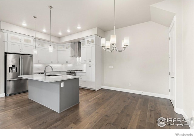 kitchen with appliances with stainless steel finishes, an island with sink, white cabinetry, wall chimney exhaust hood, and dark wood-type flooring