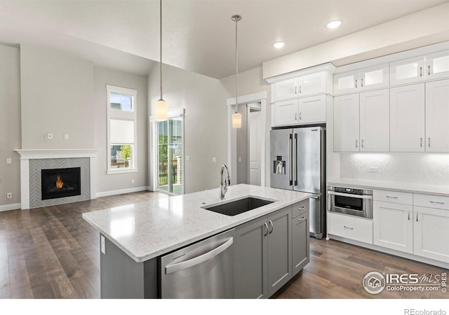 kitchen with hanging light fixtures, appliances with stainless steel finishes, white cabinetry, dark hardwood / wood-style floors, and sink