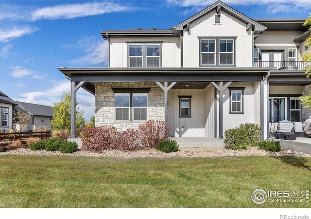 view of front of home with covered porch, a balcony, and a front lawn