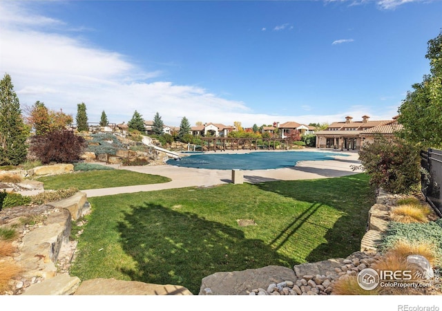 view of swimming pool featuring a patio area, a yard, and a diving board