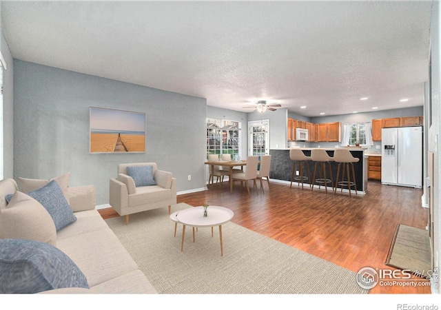 living room with a textured ceiling, ceiling fan, and hardwood / wood-style flooring