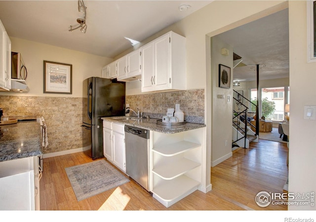 kitchen with sink, white cabinetry, stone counters, appliances with stainless steel finishes, and light hardwood / wood-style floors