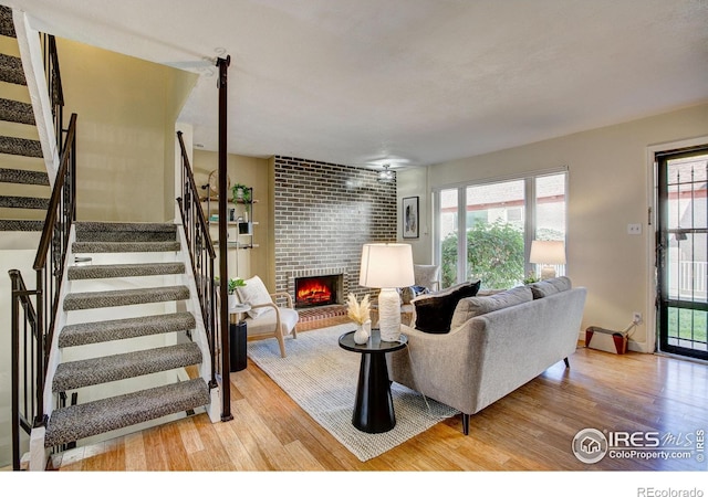 living room with a brick fireplace and light wood-type flooring