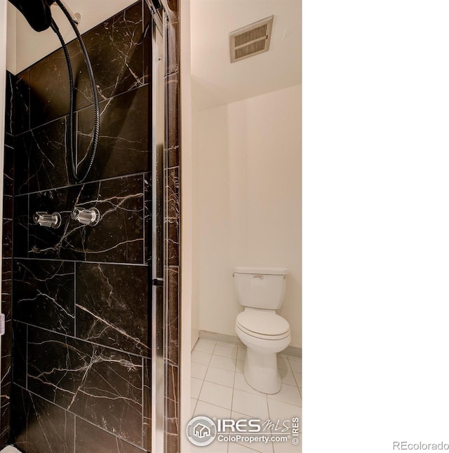 bathroom with tiled shower, toilet, and tile patterned floors