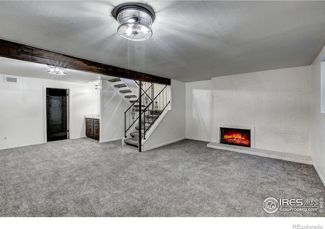 unfurnished living room featuring carpet floors, a textured ceiling, and a brick fireplace