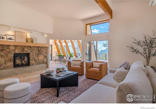 living room with beam ceiling, a fireplace, wood-type flooring, and a towering ceiling