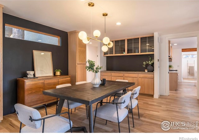 dining area with light hardwood / wood-style floors and a notable chandelier