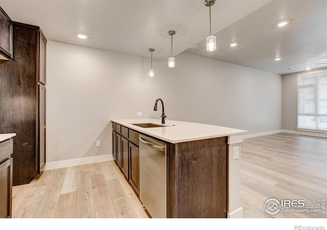 kitchen with light hardwood / wood-style flooring, stainless steel dishwasher, sink, and an island with sink