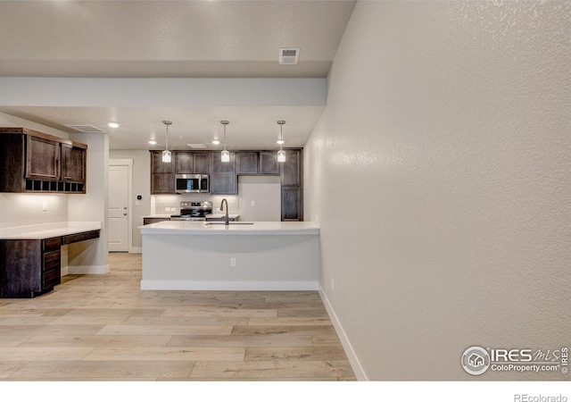 kitchen featuring sink, dark brown cabinets, light hardwood / wood-style floors, stainless steel appliances, and decorative light fixtures