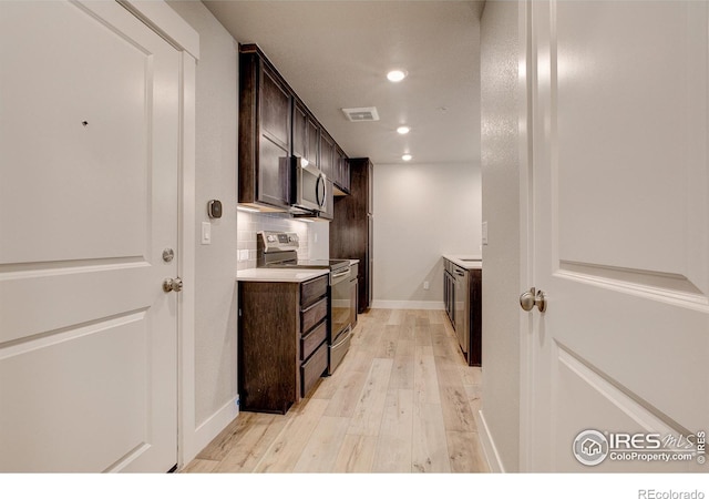 kitchen with light hardwood / wood-style floors, stainless steel appliances, dark brown cabinets, and backsplash