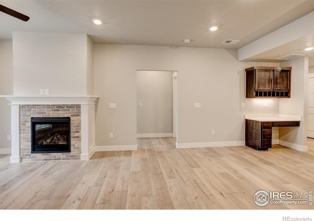 unfurnished living room with light hardwood / wood-style floors and a brick fireplace