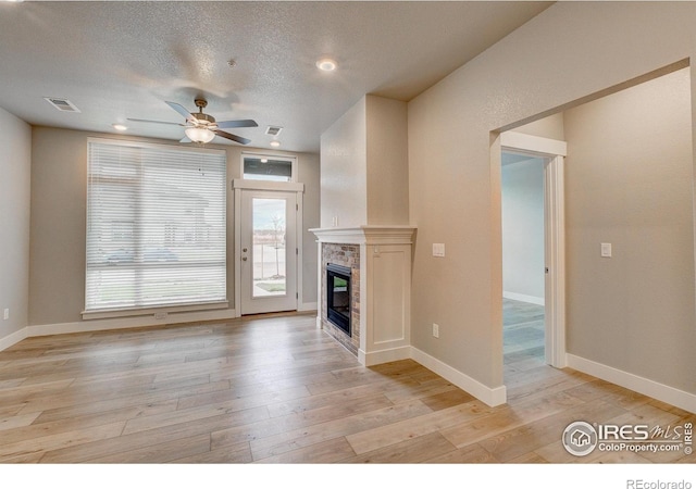 unfurnished living room with light hardwood / wood-style flooring, a textured ceiling, and ceiling fan