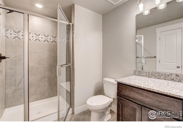 bathroom with vanity, toilet, tile patterned floors, and a shower with shower door