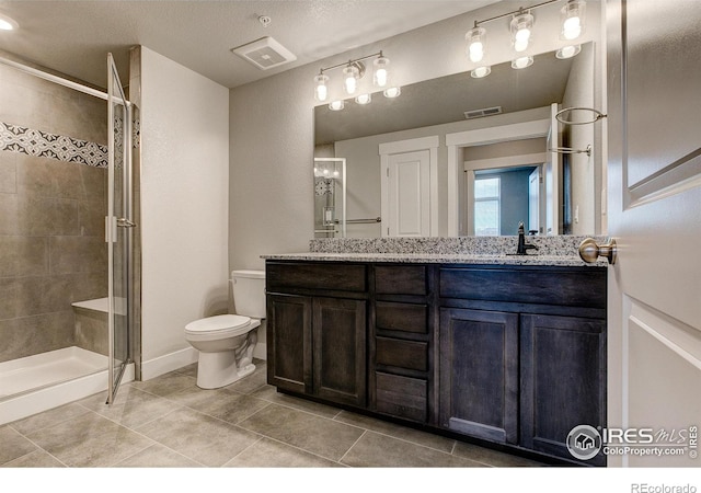 bathroom with a textured ceiling, toilet, tile patterned floors, walk in shower, and vanity