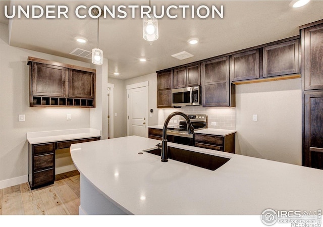 kitchen with light hardwood / wood-style floors, dark brown cabinetry, sink, and pendant lighting