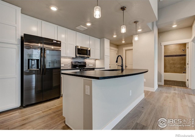 kitchen with white cabinets, a center island with sink, appliances with stainless steel finishes, sink, and decorative light fixtures