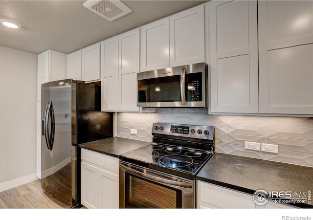 kitchen featuring appliances with stainless steel finishes, decorative backsplash, white cabinets, and light hardwood / wood-style flooring