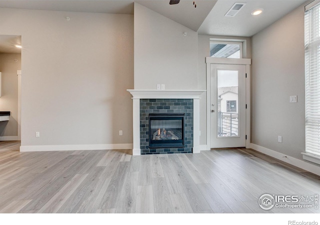 unfurnished living room featuring a wealth of natural light, light wood-type flooring, and a fireplace