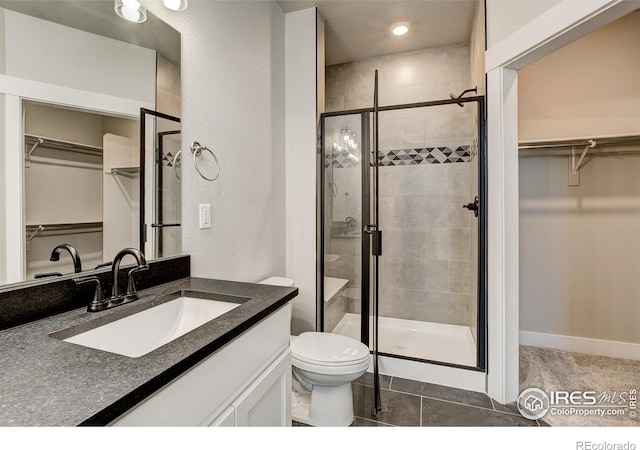 bathroom featuring vanity, toilet, walk in shower, and tile patterned flooring