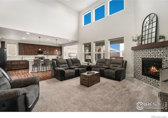 living room featuring a towering ceiling, light carpet, and a fireplace