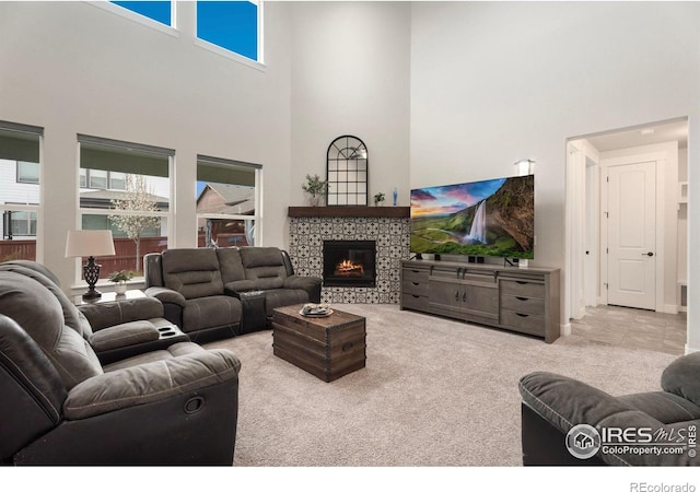 living room featuring a tile fireplace, light carpet, and a towering ceiling