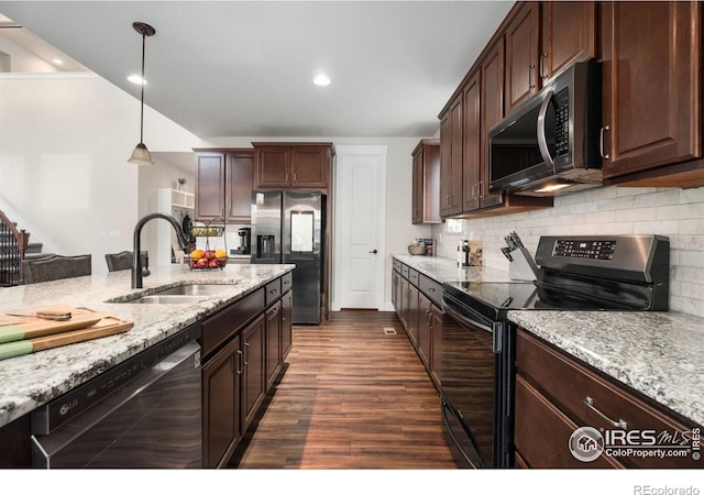 kitchen with light stone counters, dark hardwood / wood-style flooring, appliances with stainless steel finishes, sink, and decorative light fixtures