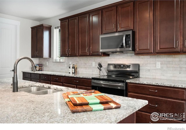 kitchen with sink, light stone countertops, stainless steel appliances, and backsplash