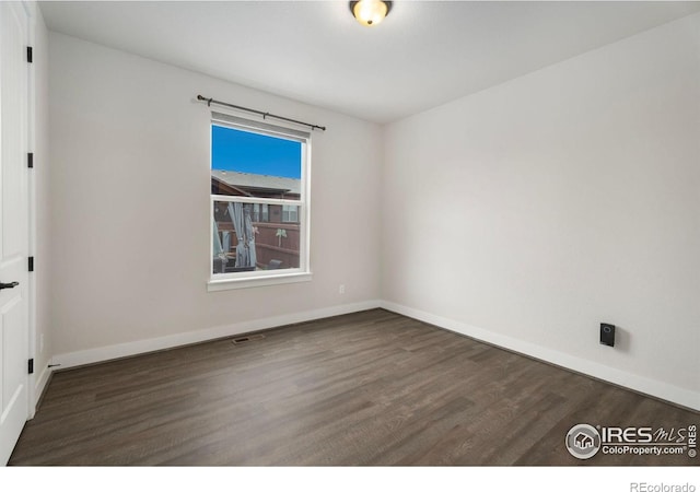 unfurnished room with dark wood-type flooring