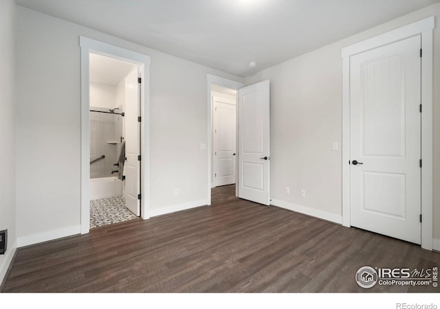 unfurnished bedroom featuring ensuite bath and dark hardwood / wood-style floors