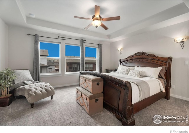 carpeted bedroom featuring a raised ceiling and ceiling fan