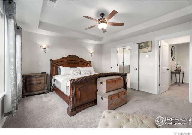 carpeted bedroom featuring ceiling fan and a raised ceiling