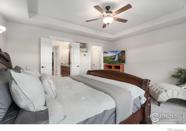 carpeted bedroom featuring connected bathroom, ceiling fan, and a raised ceiling