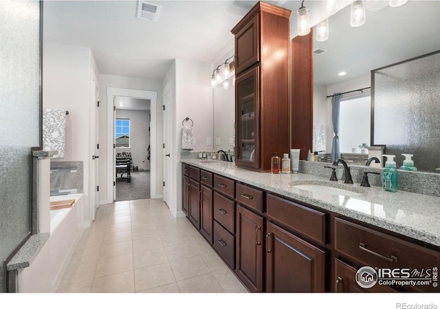 bathroom featuring vanity, a healthy amount of sunlight, tile patterned flooring, and a bath