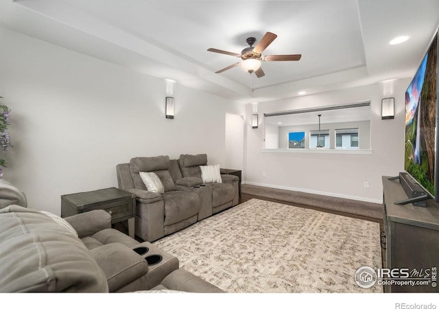 carpeted cinema with a raised ceiling and ceiling fan