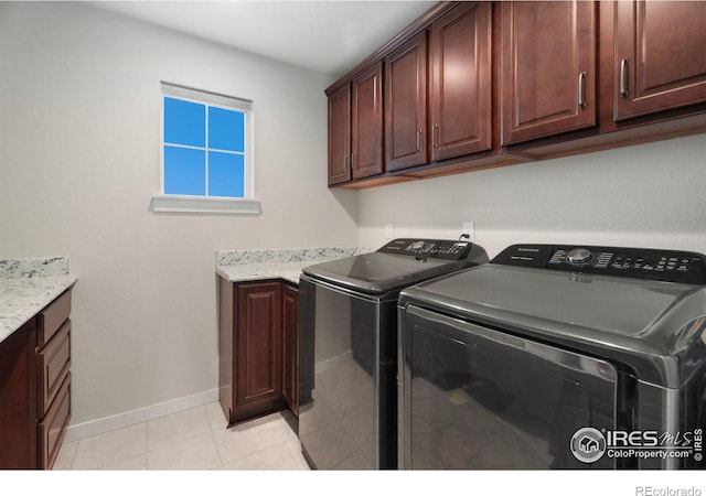 laundry area with washing machine and dryer, light tile patterned floors, and cabinets